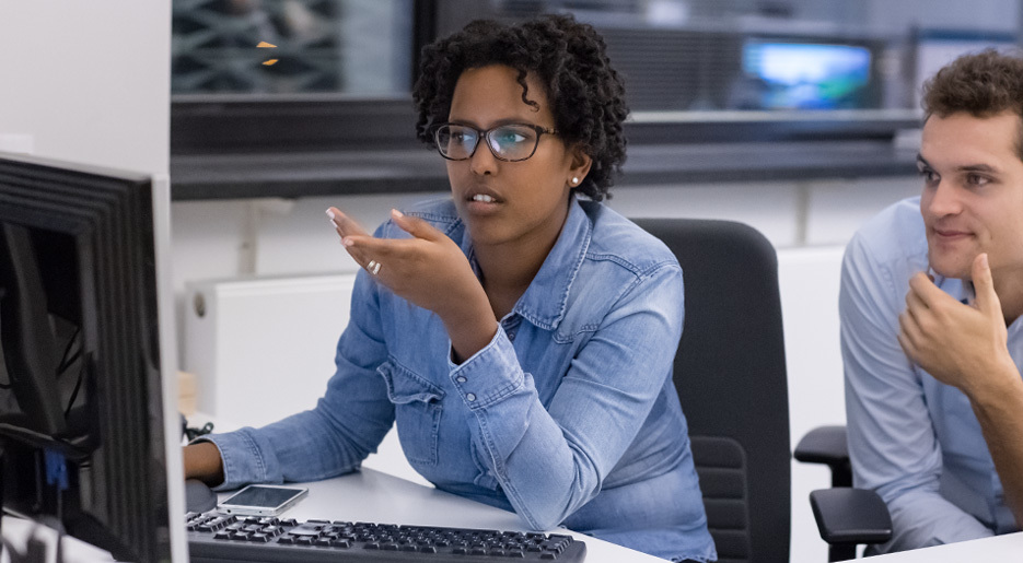 Zwei Personen unterhalten sich vor dem Computer