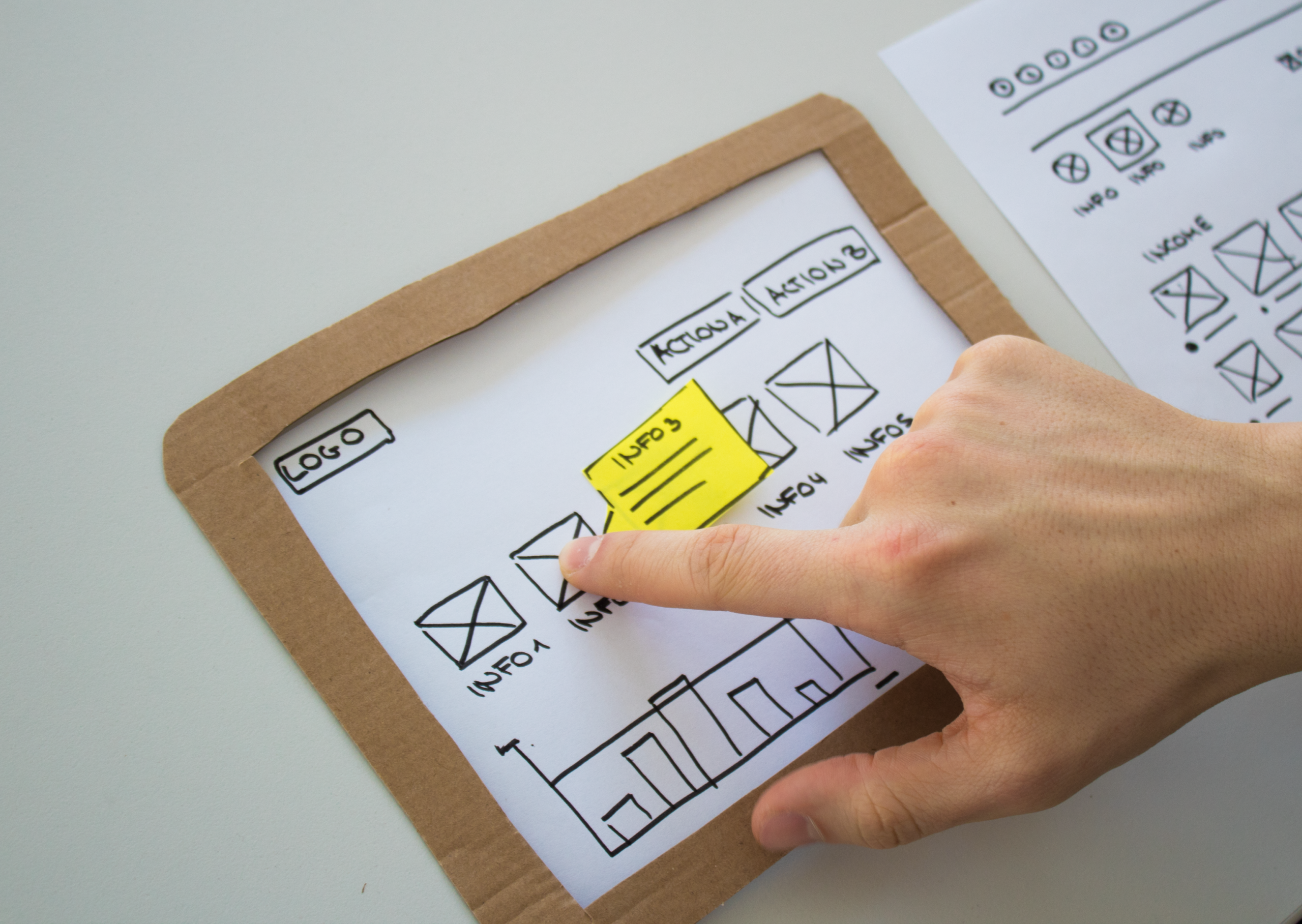 UID_Insight_KI-Prototyp_Papierprototyp_Klick-Test Ein Finger tippt auf einen Papierprototyp einer Tablet-Oberfläche